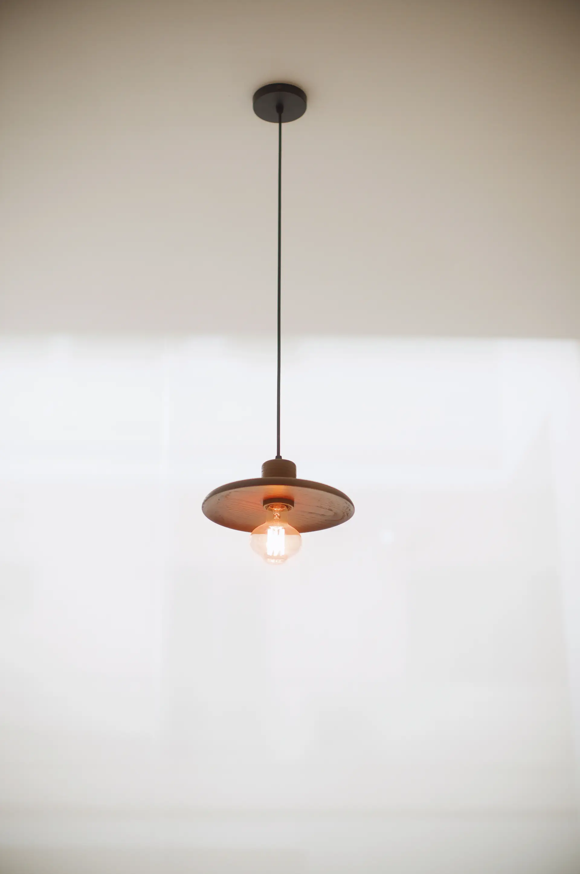 Minimalist hanging lamp casting warm controlled glow onto interior wall