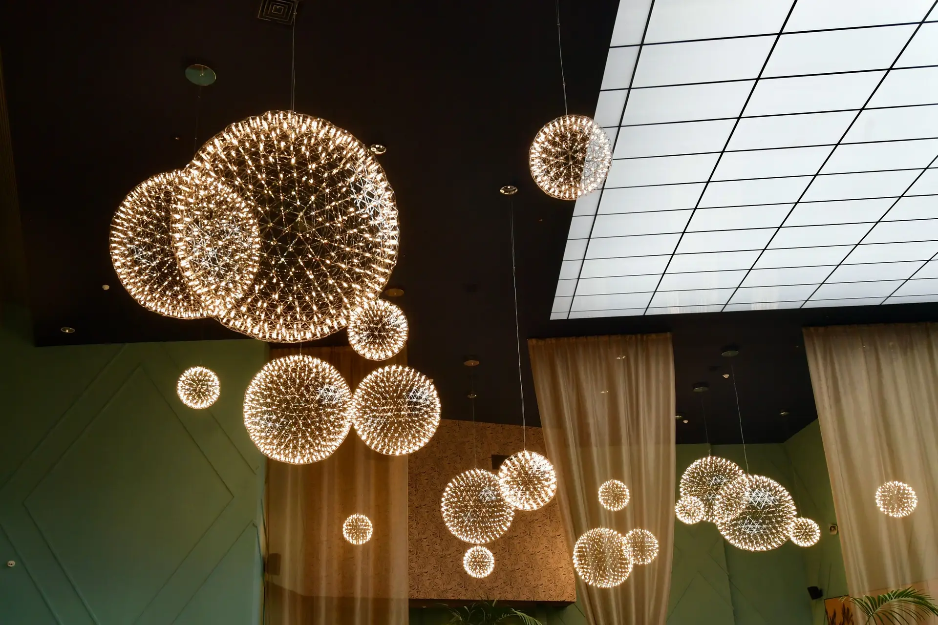 Architectural interior illuminated with warm spherical sculptural chandeliers